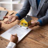 Reliable real estate agent giving keys to couple, male female hands close up receiving the house keys after the dealing.